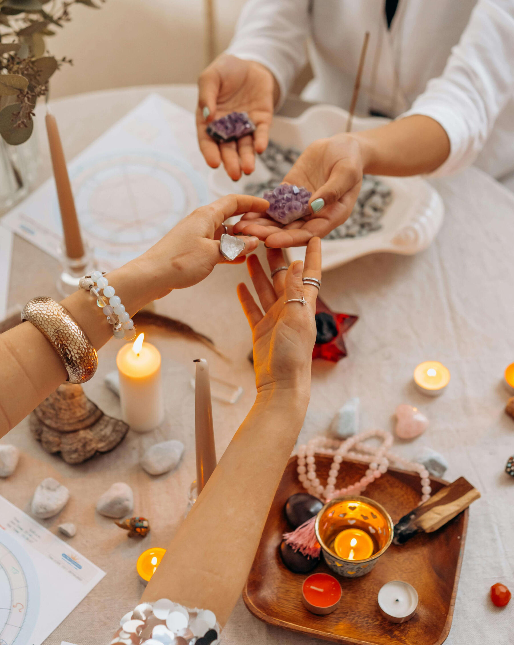 Photo of two women holding crystals at a table with many crystals, cancles and mala beads.